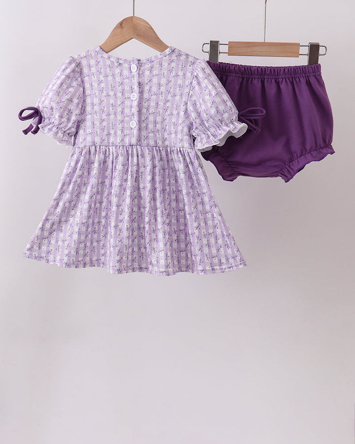 Purple checkered dress and shorts on hangers against a white background