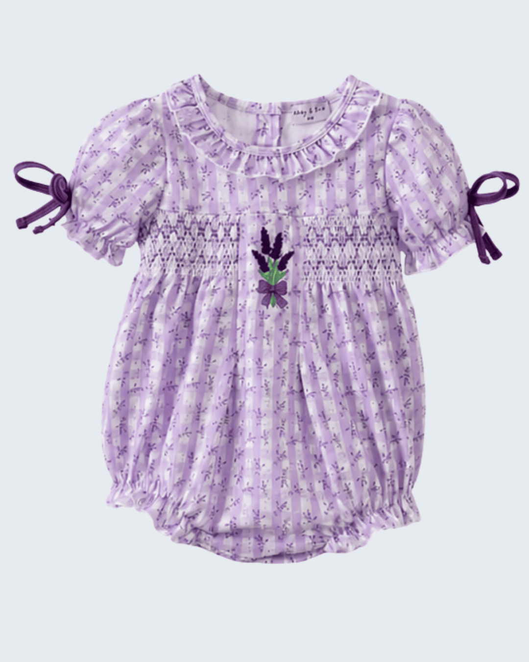 Purple floral baby romper with ruffled sleeves on a light purple background