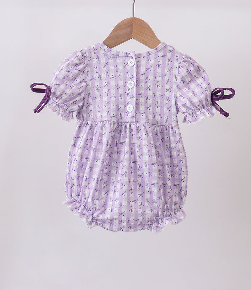 Lavender baby romper with ruffles on a wooden hanger against a white background