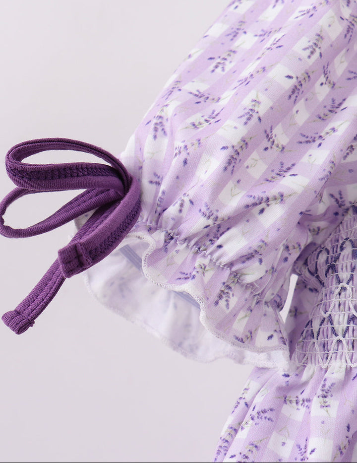 Close-up of a purple dress with floral pattern on a light gray background