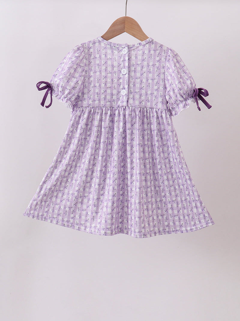Purple checkered dress with bow sleeves on a hanger against a white background