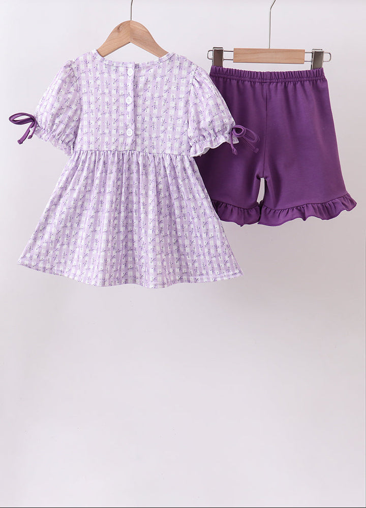 Purple and white checkered dress with matching shorts on hangers against a white background