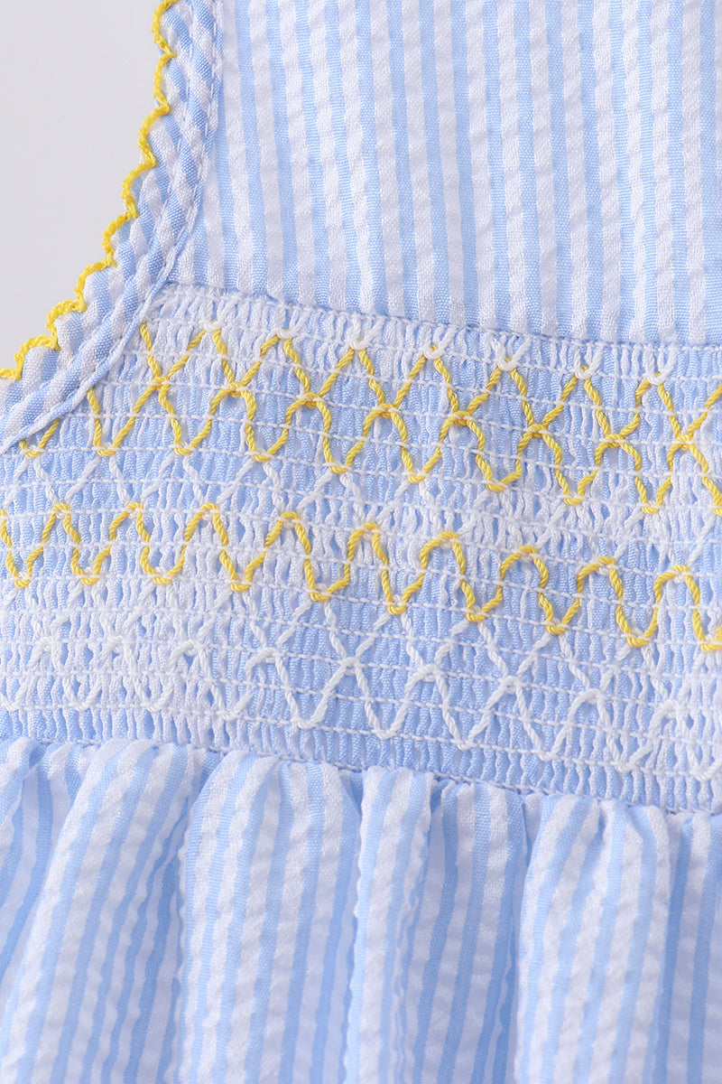 Close-up of a blue and white striped fabric with yellow embroidery