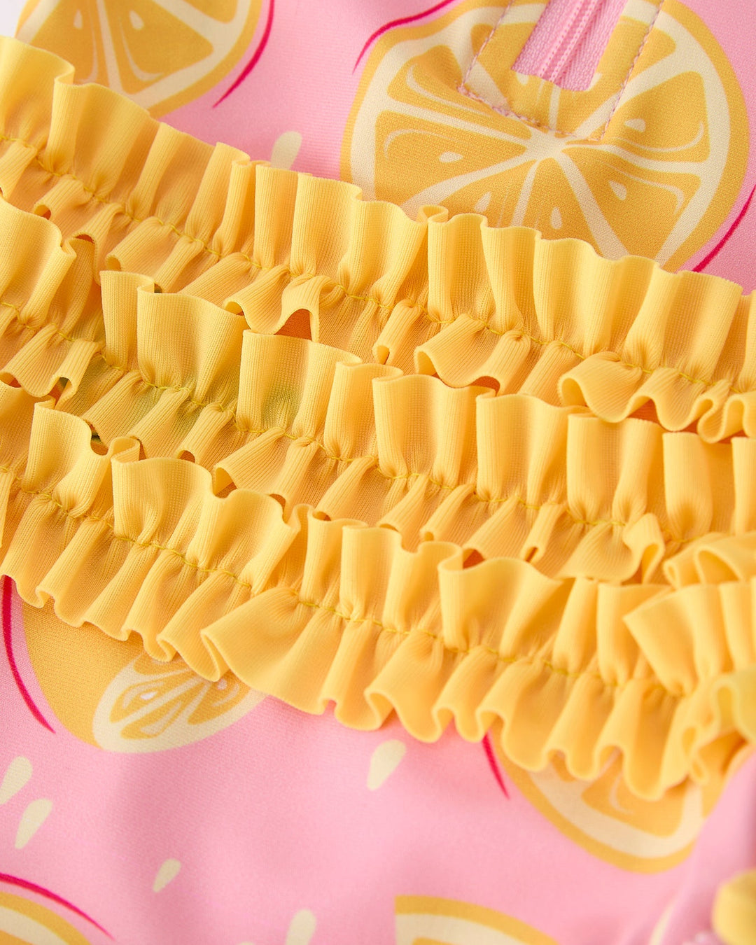 Close-up of a yellow ruffled fabric with pink background featuring lemon slices
