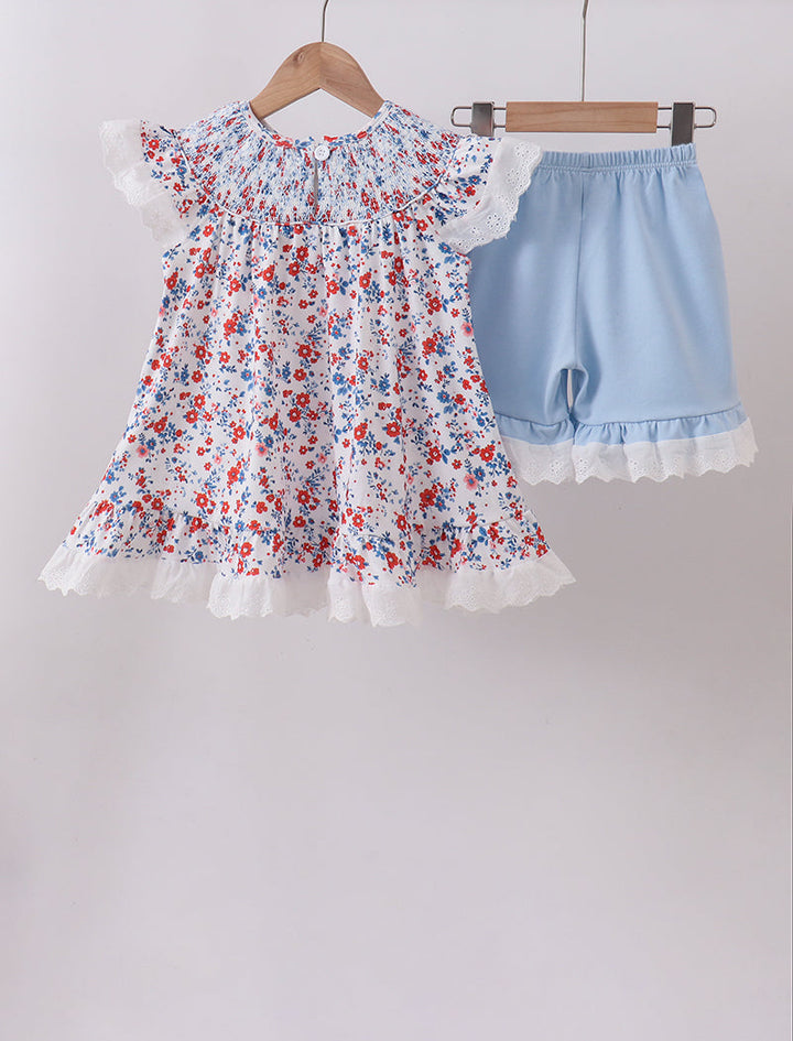 Floral dress and blue shorts on hangers against a white background