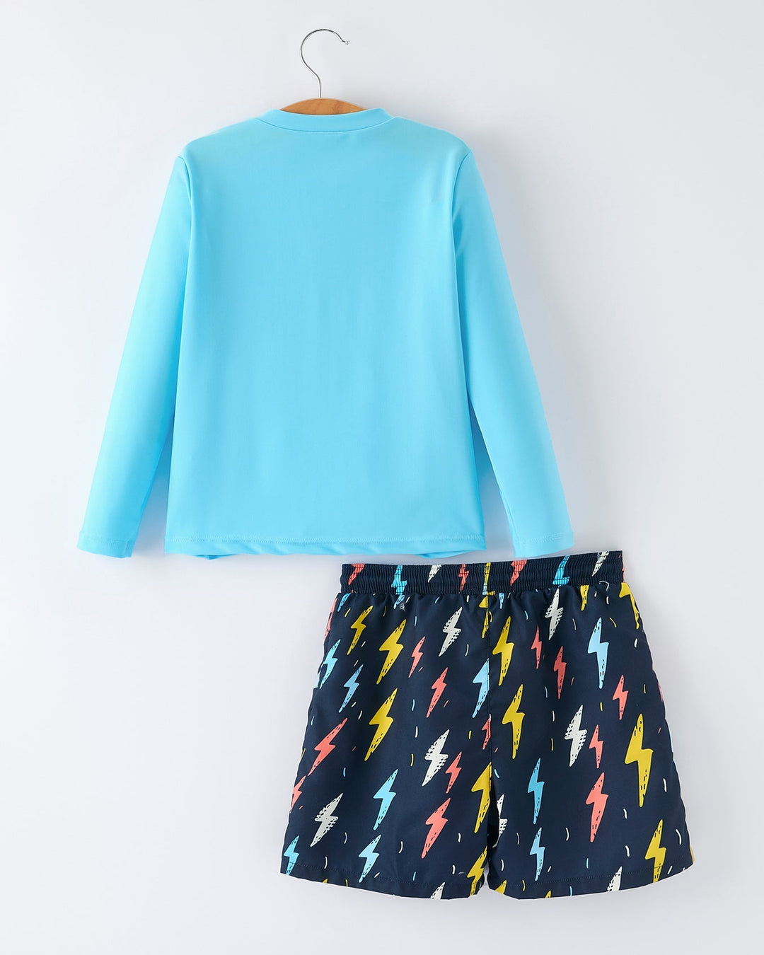 Light blue long-sleeve top and navy shorts with colorful lightning bolt pattern on a white background