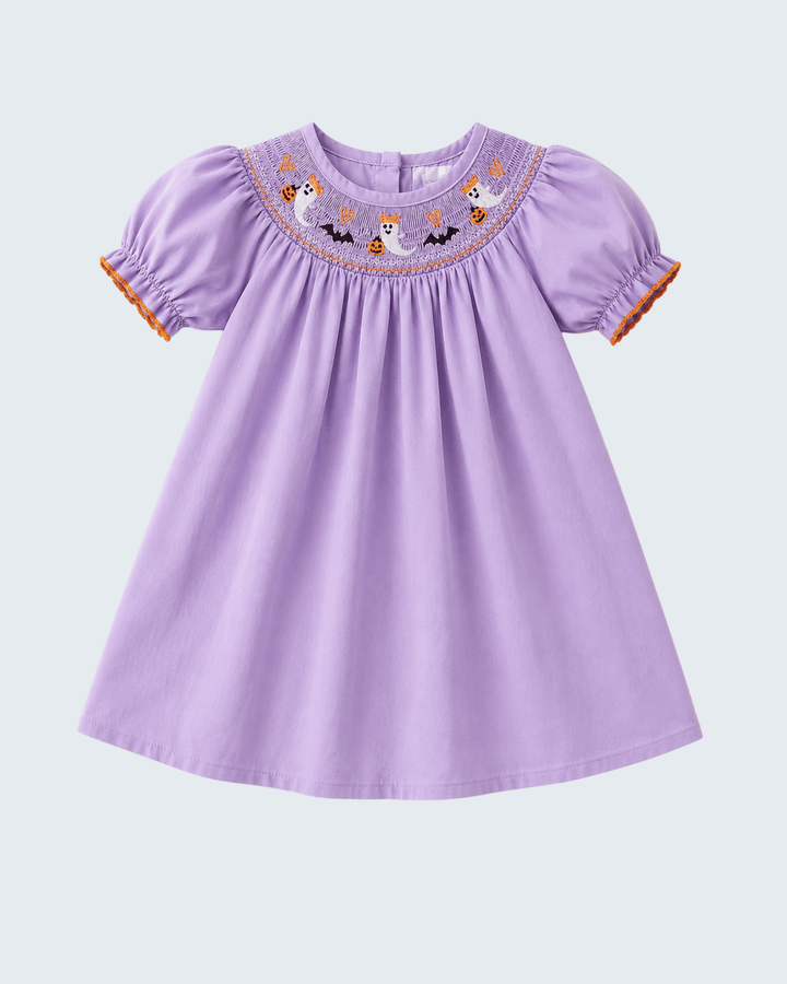 A lavender purple baby dress with short puff sleeves, featuring a smocked neckline decorated with embroidered cartoon ghosts, bats, and pumpkins, finished with orange ruffle trim at the sleeve cuffs.