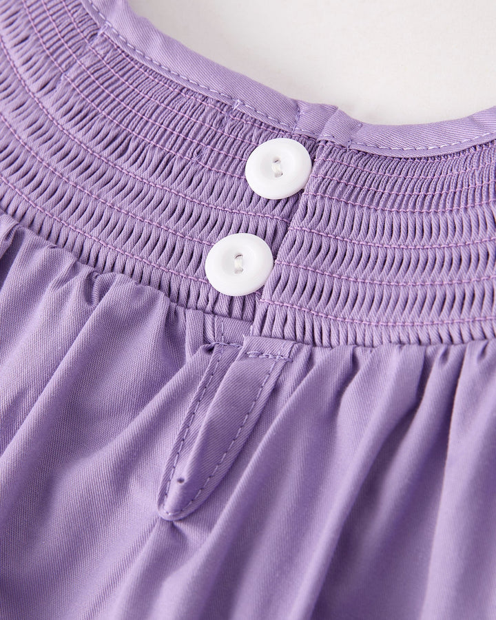 Lavender smocked yoke dress with two white buttons and stitched detail