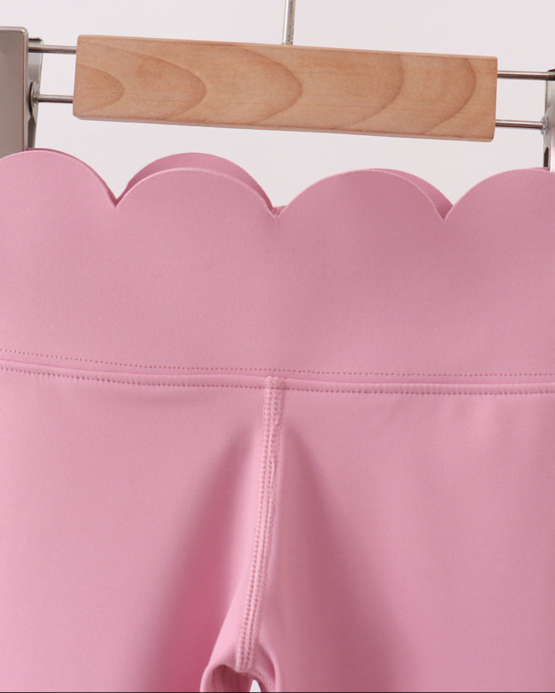 Pink leggings on a wooden hanger against a white background