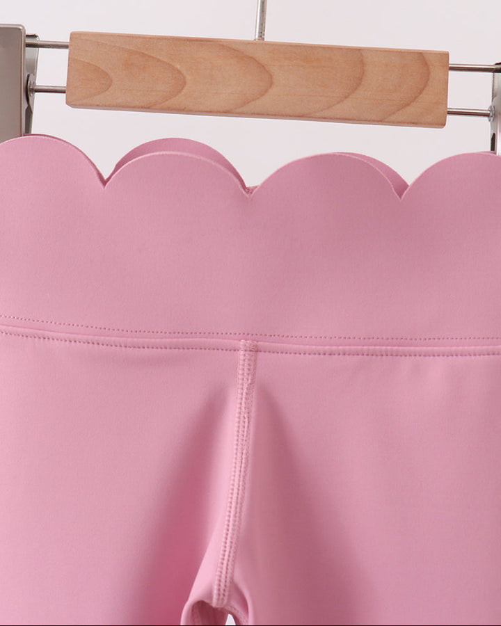 Pink leggings on a wooden hanger against a white background