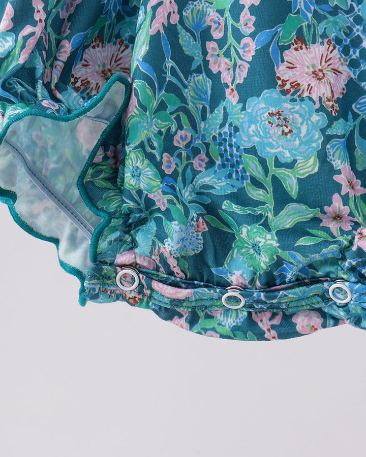 Blue floral baby romper close-up with ruffled trim and snap placket detail