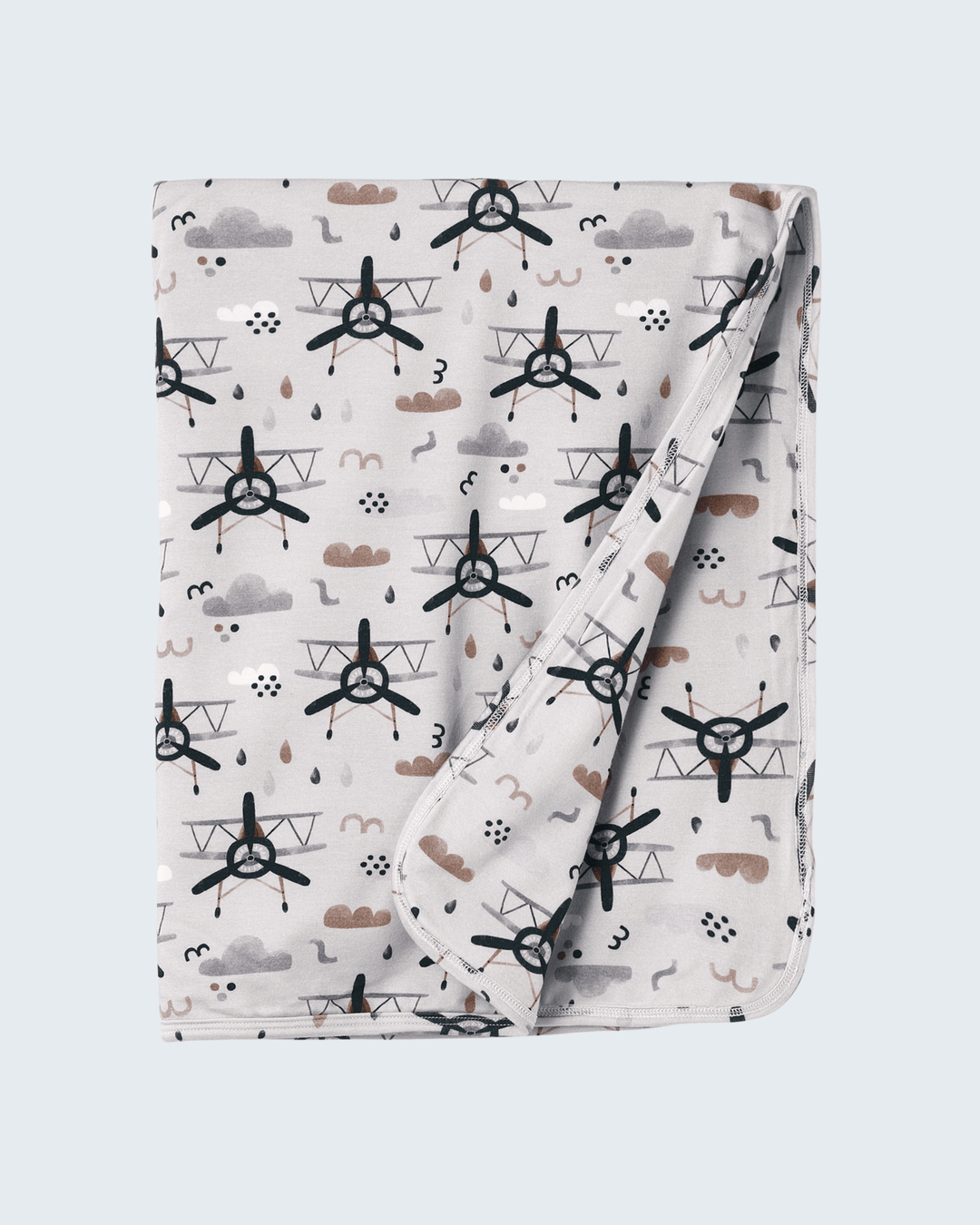 Bamboo baby stroller blanket with airplane print, clouds and raindrops, folded corner