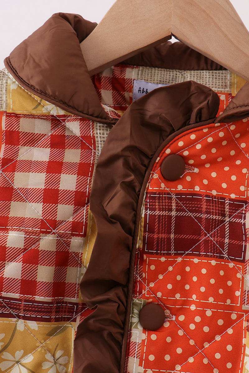 Hooded patchwork jacket detail with plaid and orange polka dot panels, brown trim, buttons