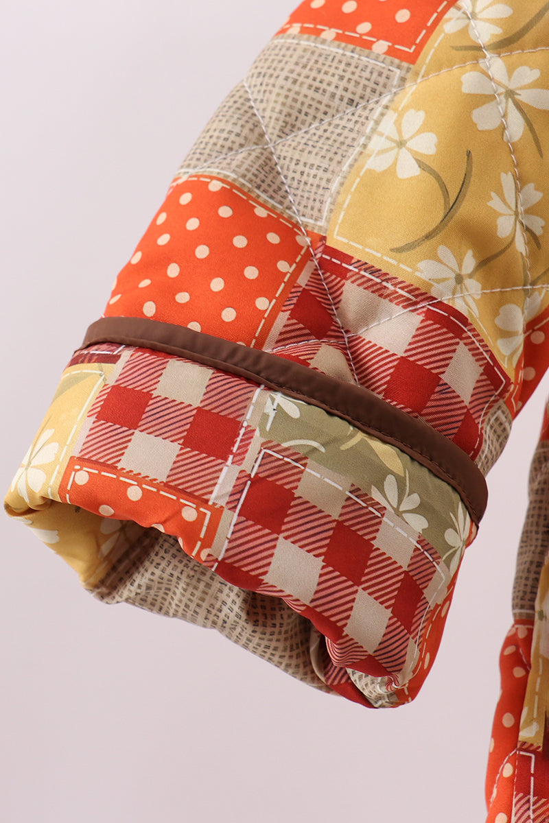 Side view of patchwork hooded jacket sleeve with plaid and floral blocks, brown trim