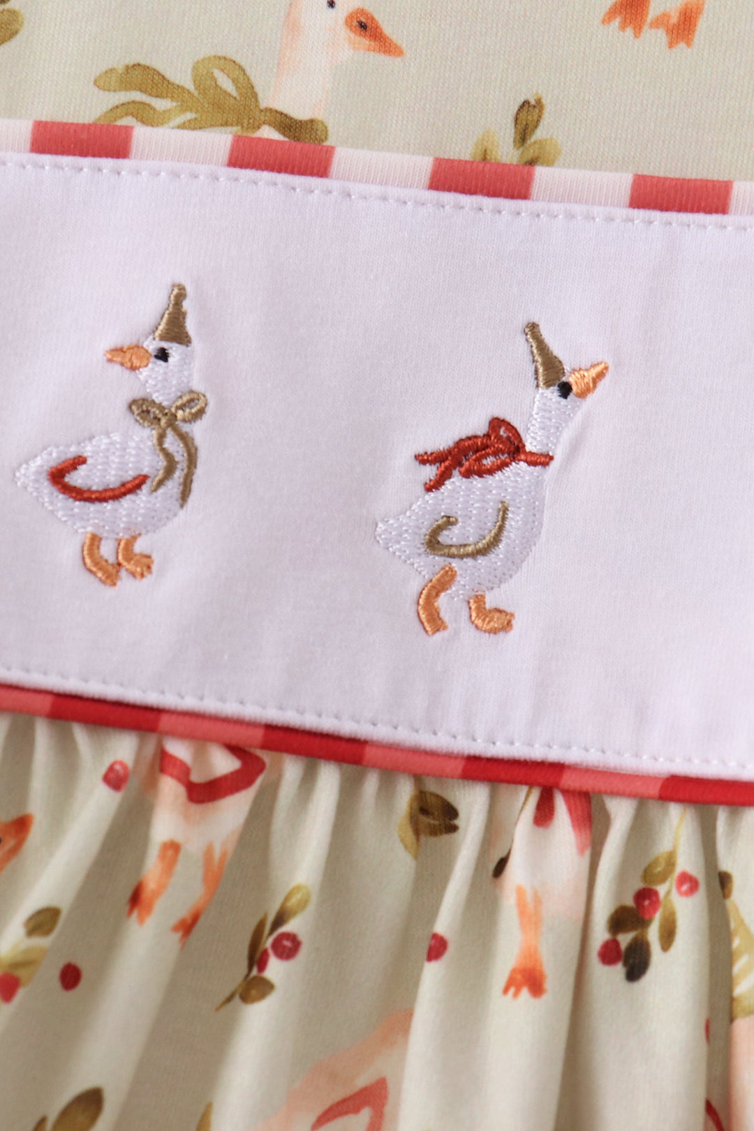 Cream dress bodice with colorful farm animal embroidery and red trim at the waist