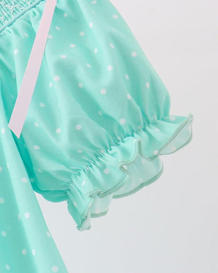 Light mint dress sleeve with ruffled cuff and bow ties over dotted fabric