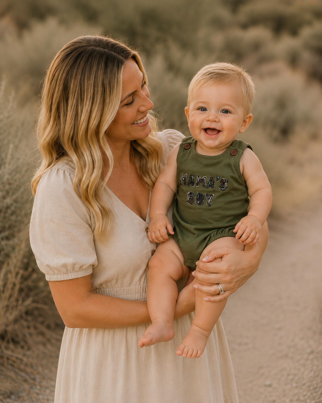 Woman holding a baby in a green outfit with &