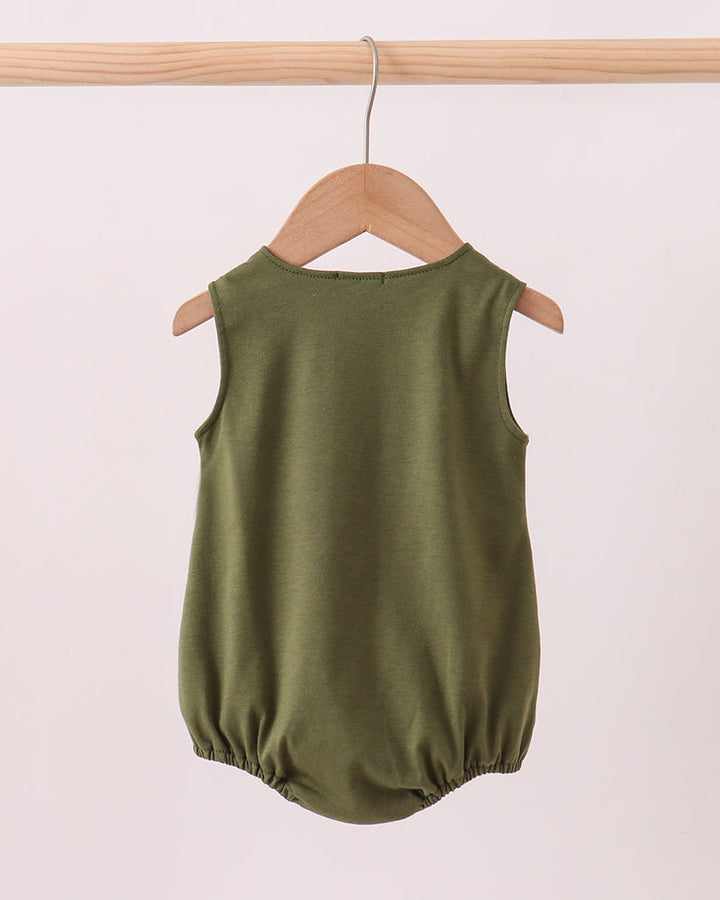 Green baby romper on a wooden hanger against a light pink background