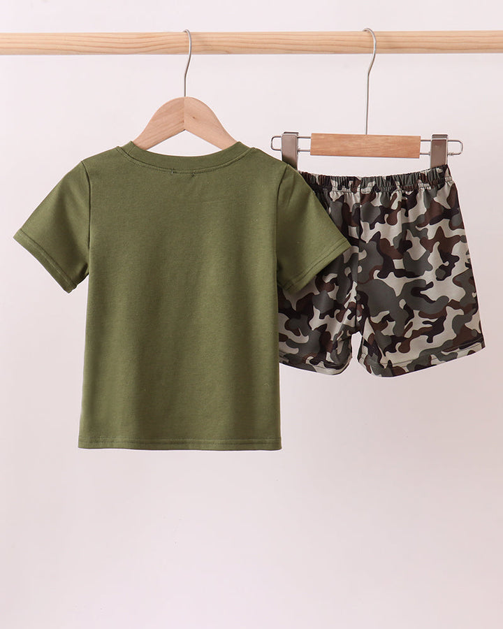 Green t-shirt and camouflage shorts on hangers against a white background