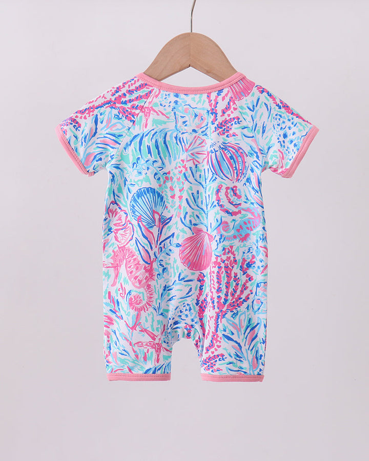 Baby romper with colorful sea-themed pattern on a wooden hanger against a light background