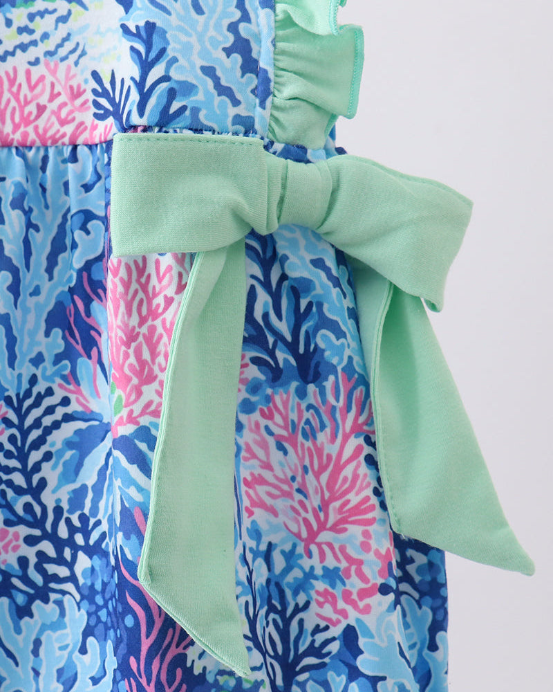 Close-up of a romper with a blue and pink floral pattern and green bow on a white background