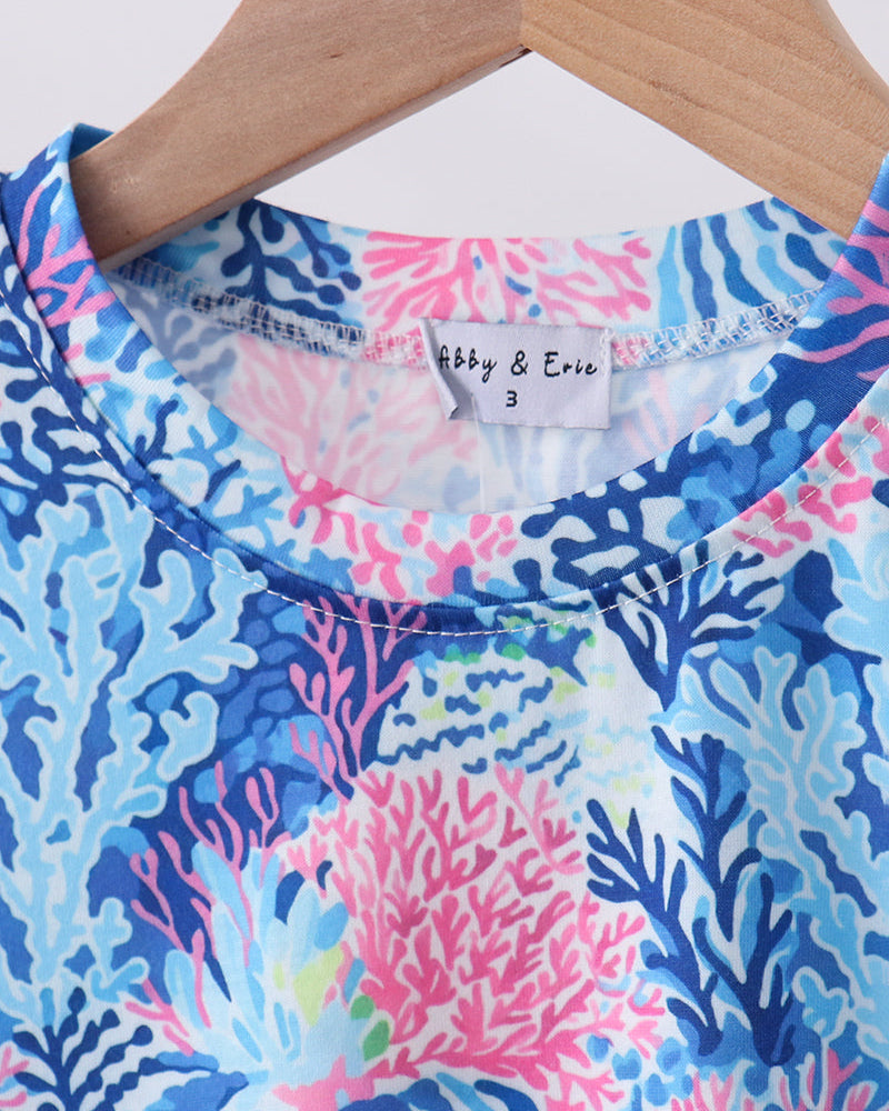 Colorful coral patterned shirt on a hanger .