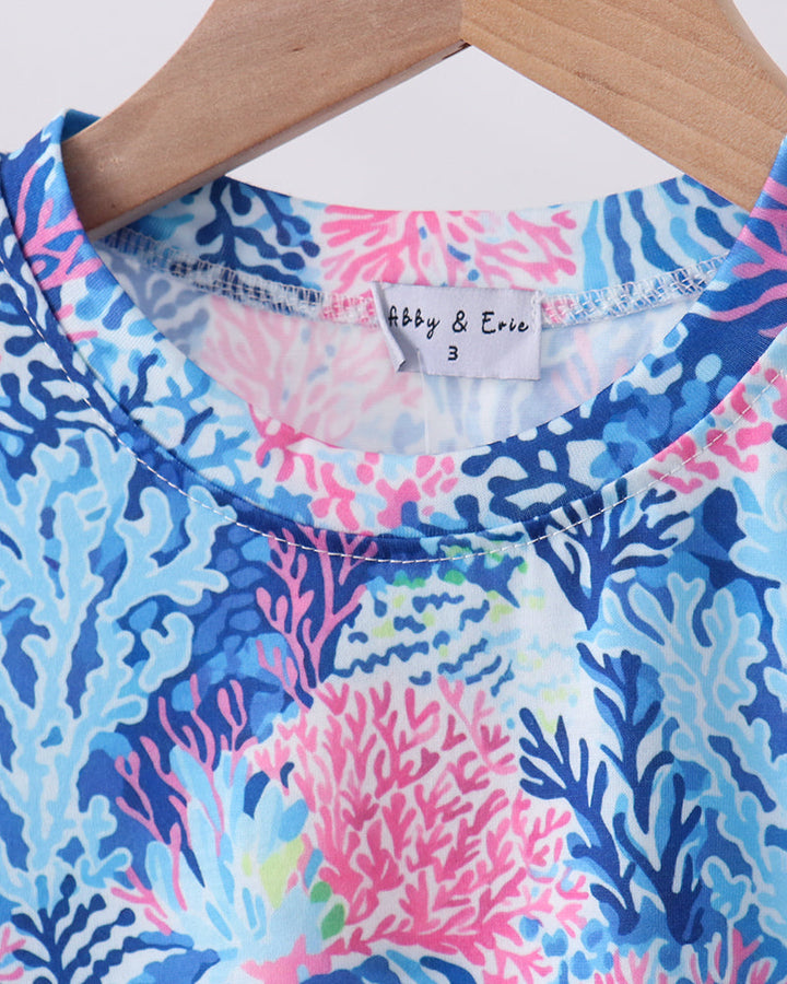 Colorful coral patterned shirt on a hanger .