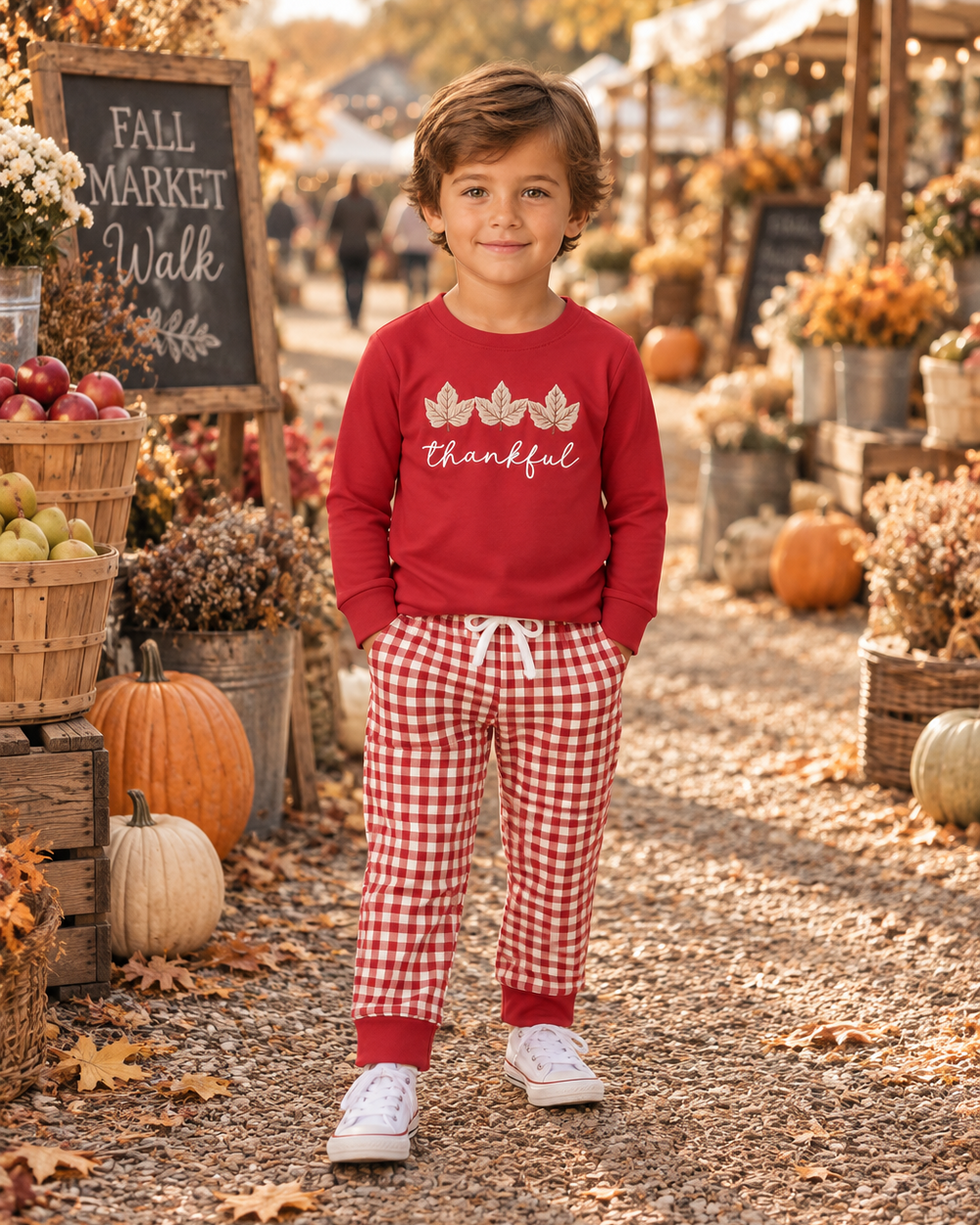 Child wearing maroon long-sleeve top with leaf thankful embroidery and gingham pants