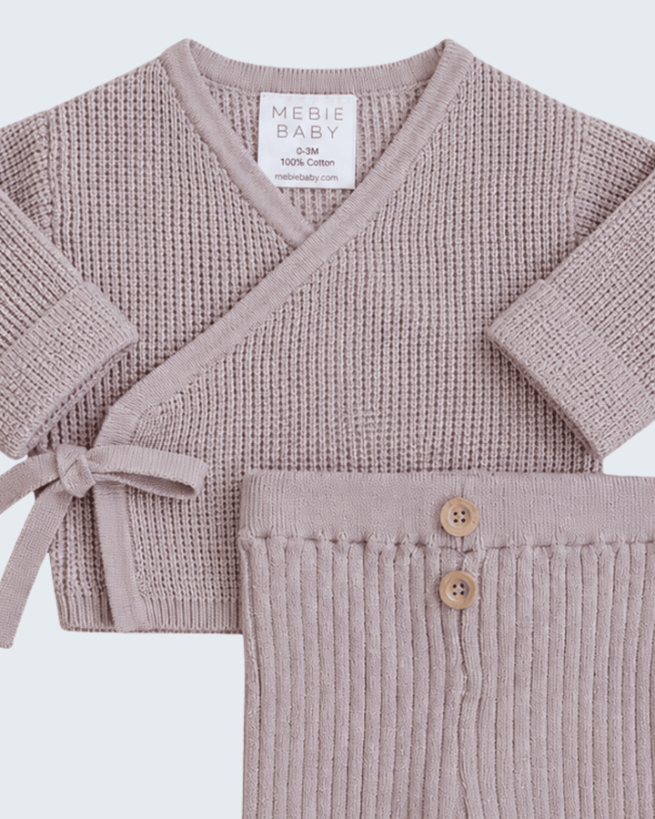 A baby knit two-piece set in dusty mauve, featuring a long-sleeve wrap cardigan with a tie detail and matching ribbed pants with two wooden buttons, from the brand MEBIE BABY.
