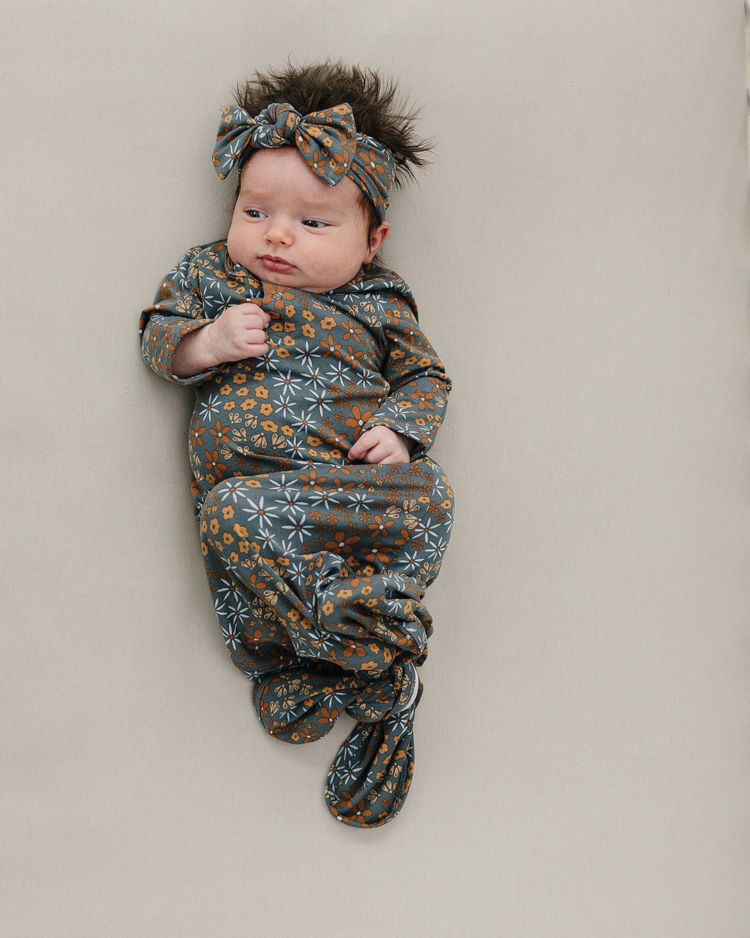 Dark blue floral head wrap knotted at top, worn by a baby