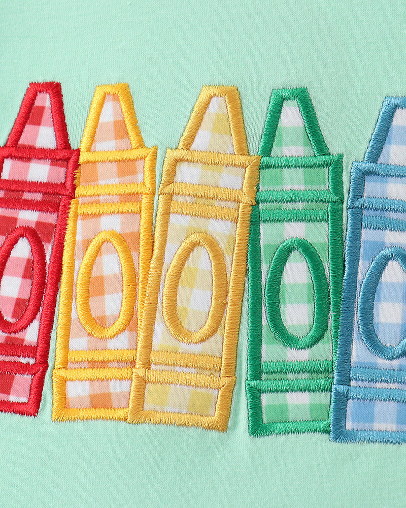 Embroidered crayons on green shirt