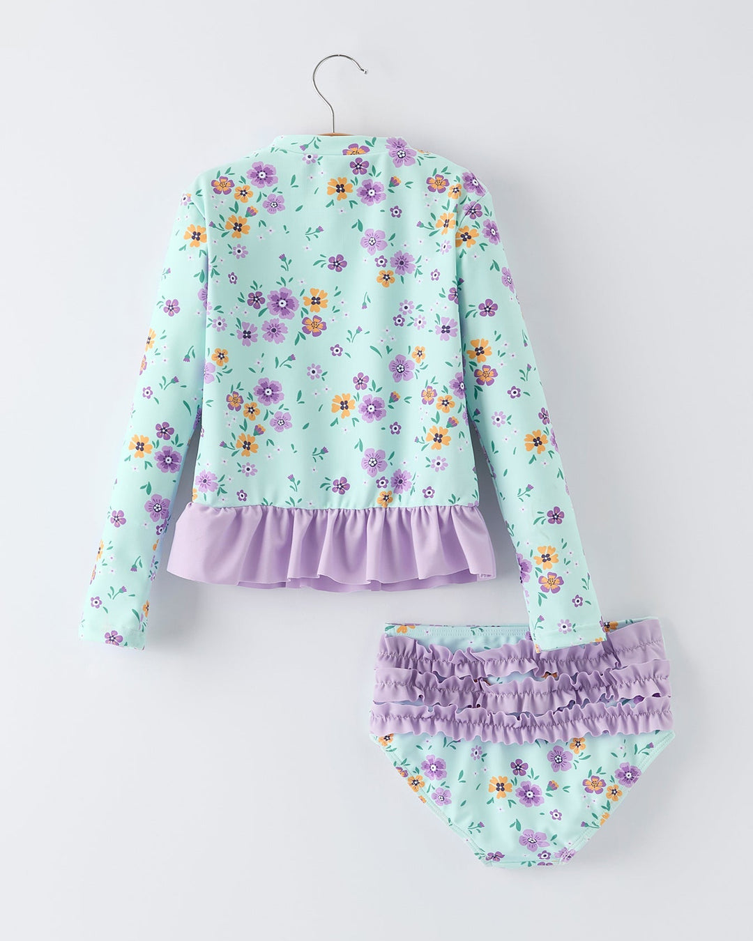 Floral baby girl swimsuit set with ruffled details on a white background