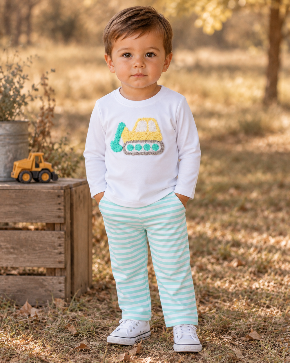 Toddler wearing white top and mint striped pants with yellow and green excavator graphic