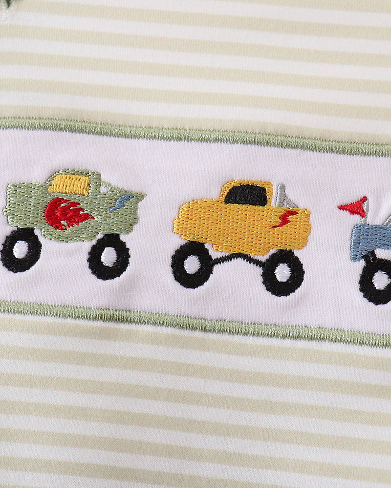 Close-up of striped baby bubble romper with monster truck embroidery and green trim