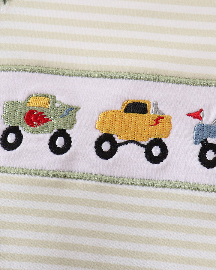 Close-up of striped baby bubble romper with monster truck embroidery and green trim