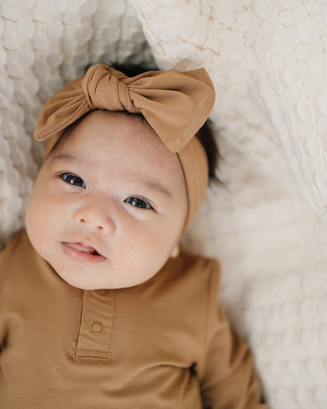 Mustard bamboo head wrap with tied bow on top, worn by baby