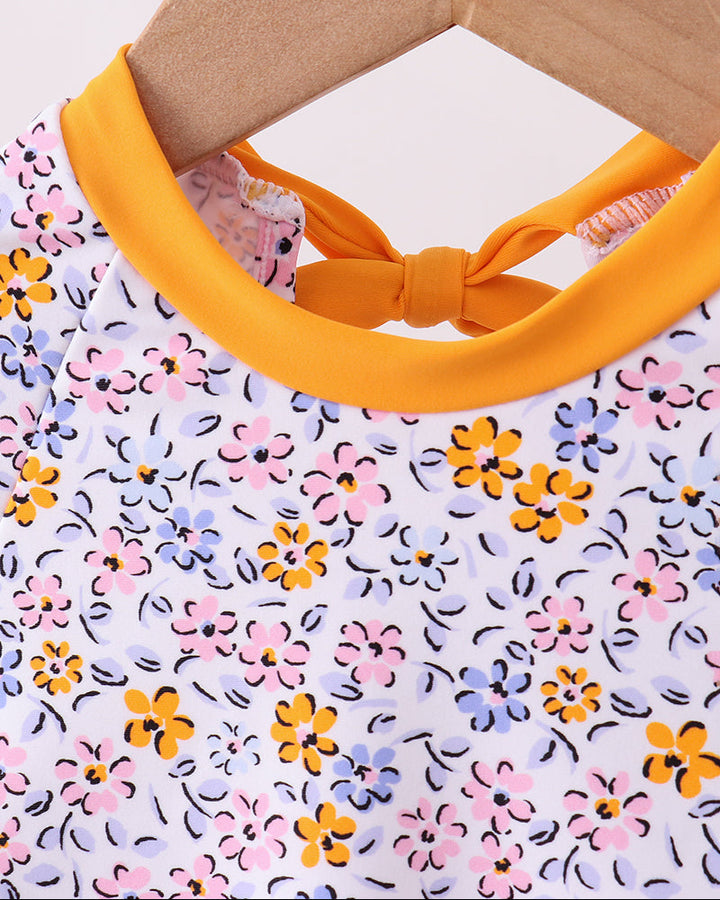 Floral-patterned rashguard with yellow trim on a hanger against a white background