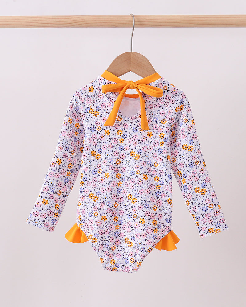 Floral rashguard with orange trim on a hanger against a white background