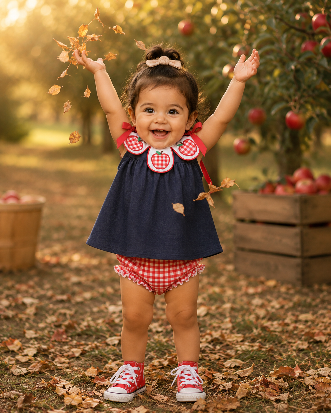Girl wearing navy denim dress with red gingham apple trim and red gingham bloomers