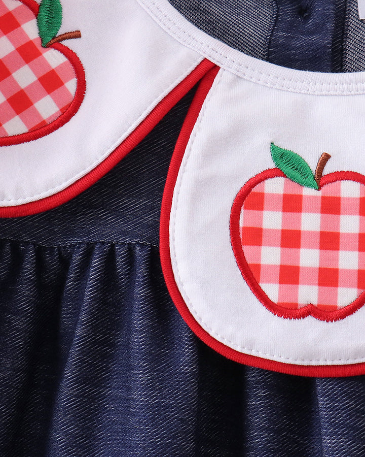Close-up: red apple applique on white yoke with green leaf and red trim