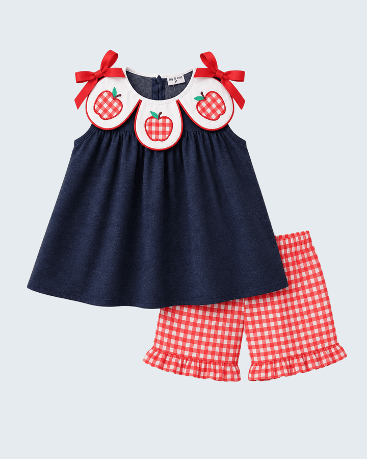 Navy sleeveless dress top with red apple applique bib, paired with ruffle gingham shorts