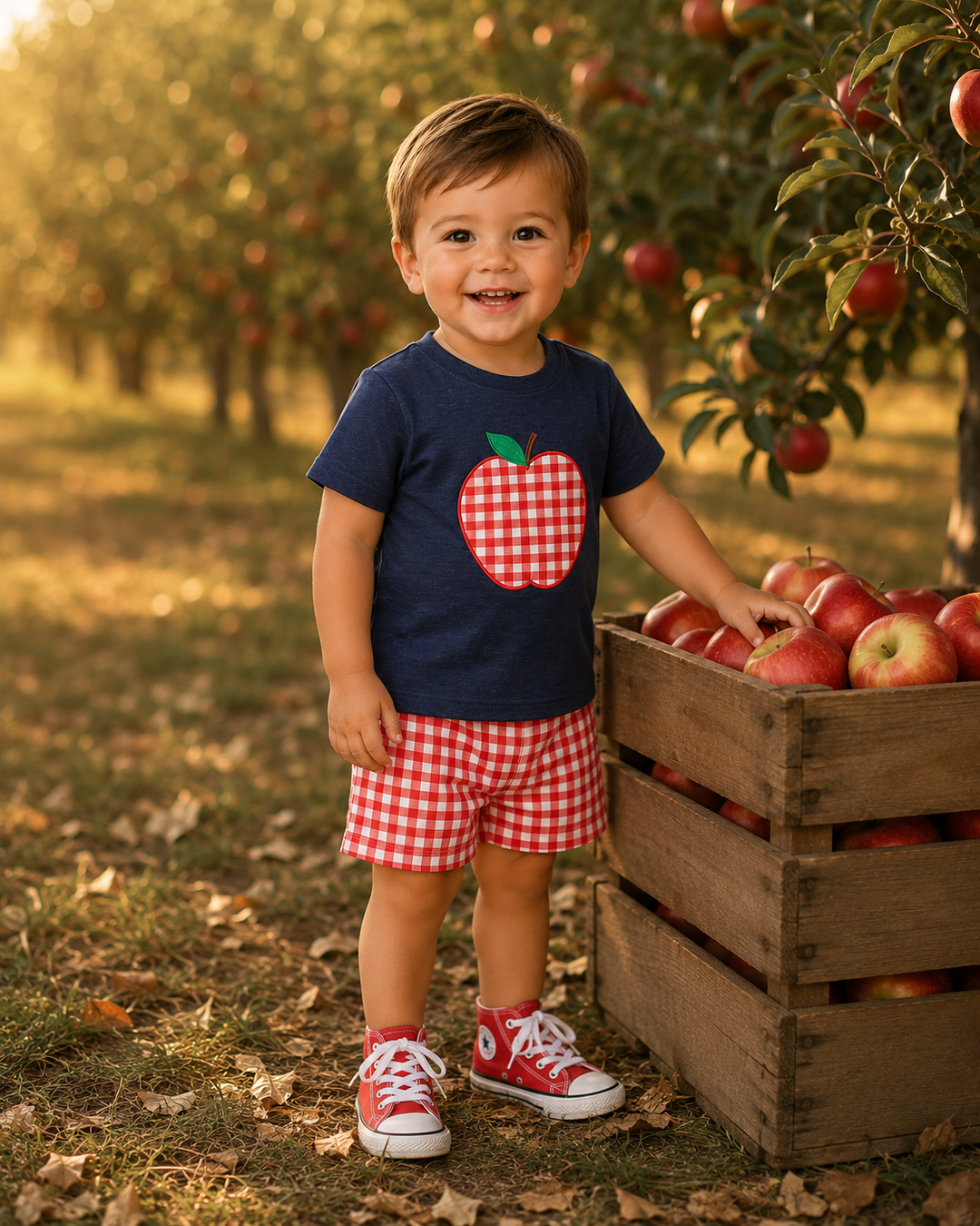 Navy apple-applique T-shirt with red plaid denim shorts, worn by child