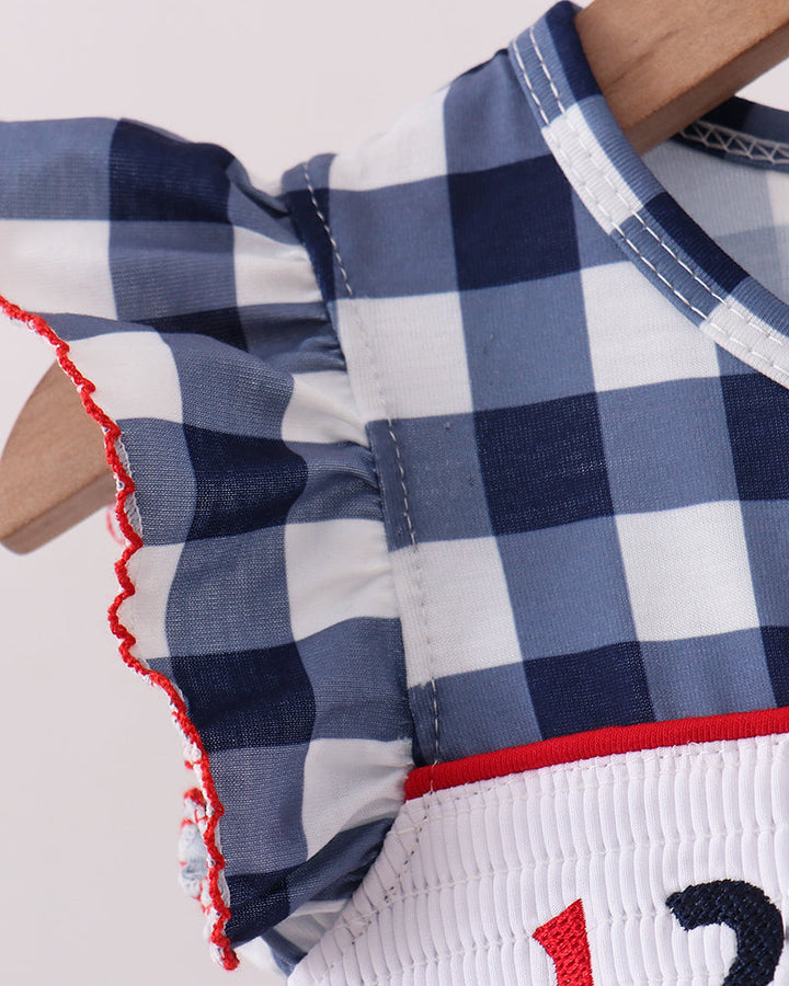 Navy gingham dress with red-trimmed ruffles and white smocked band detail