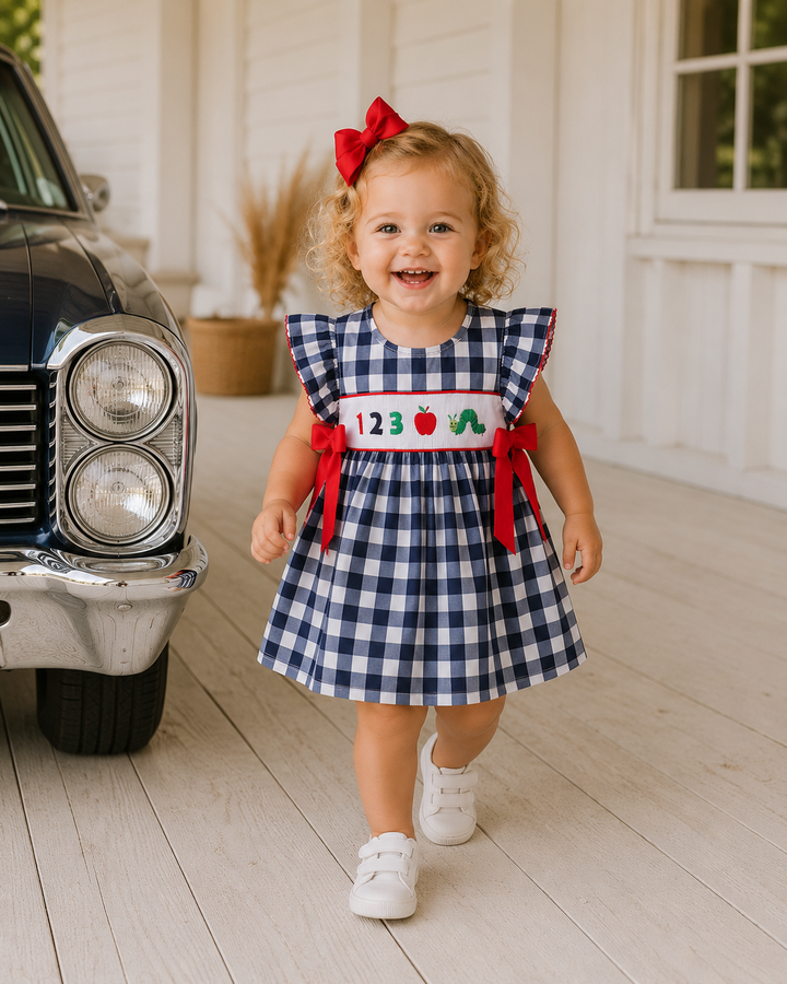 Navy gingham smocked dress with red bow accents and apple graphic bodice