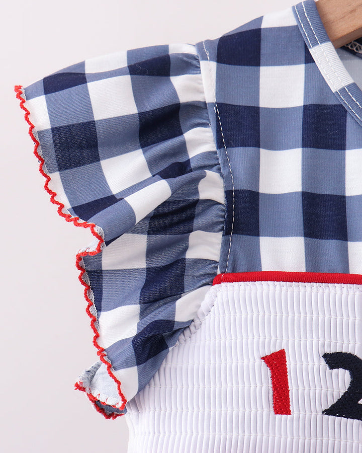 Navy gingham ruffled sleeve with white smocked waistband and red trim