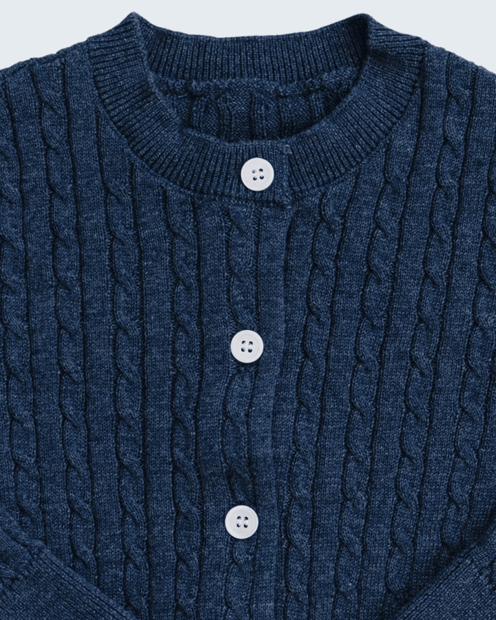 Close-up of a navy blue cable-knit cardigan sweater with a ribbed crew neck and three white buttons.