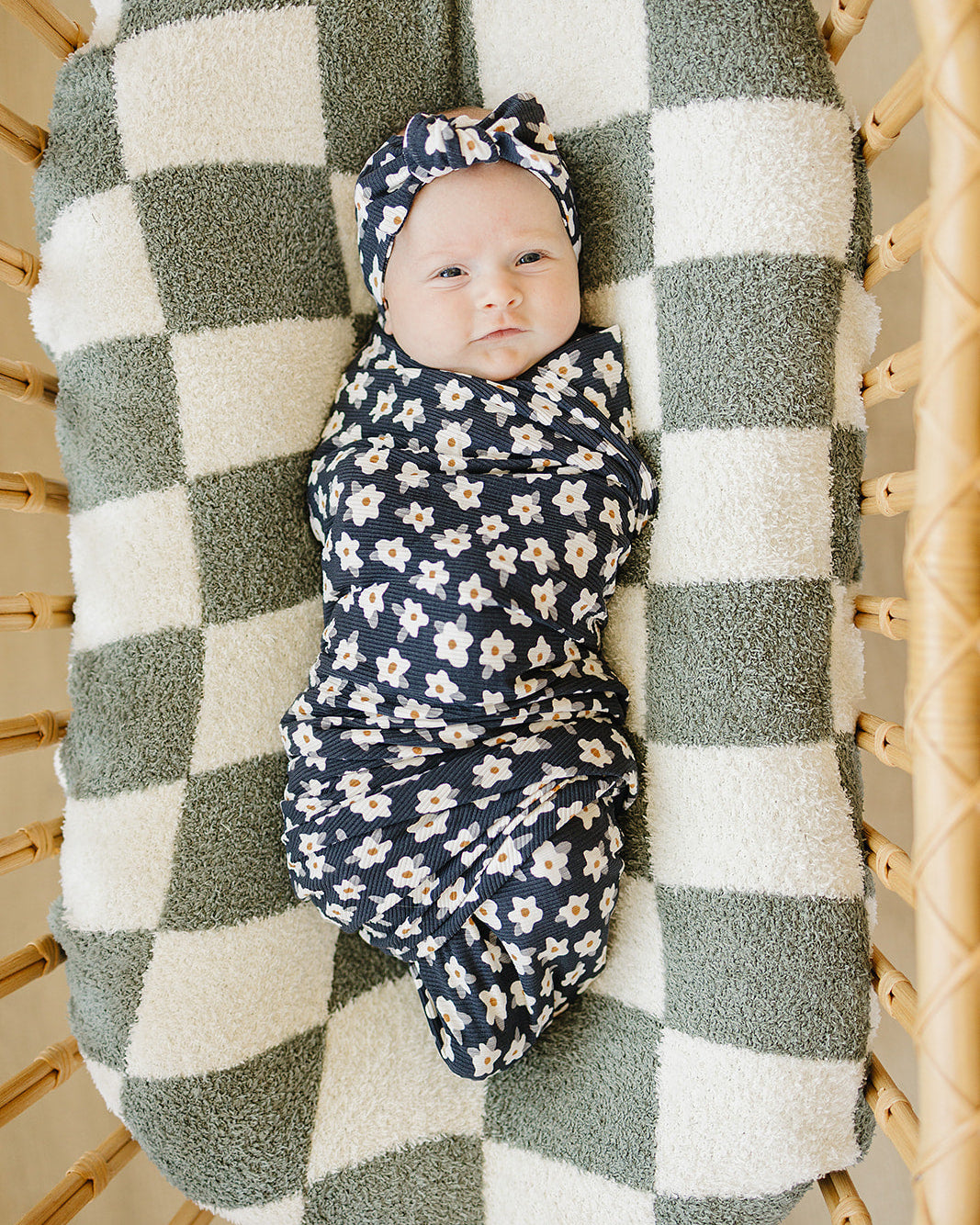 Navy daisy baby head wrap with knotted front on seated infant