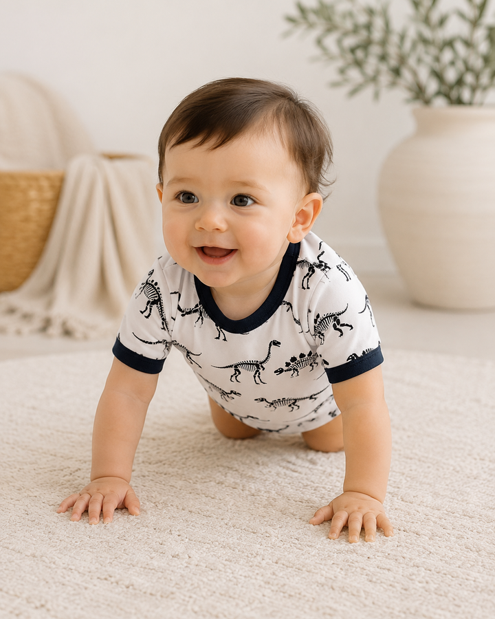 Baby boy crawling wearing a dinosaur print romper