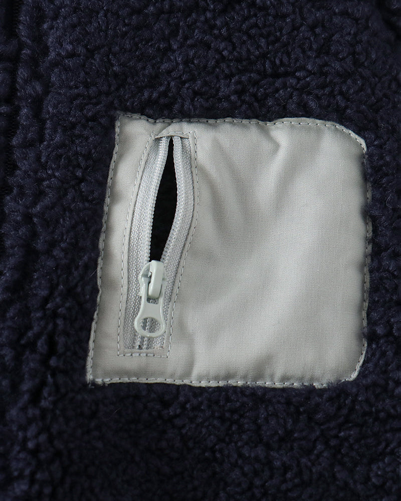 Navy fleece jacket close-up of chest pocket with zipper tab and label patch