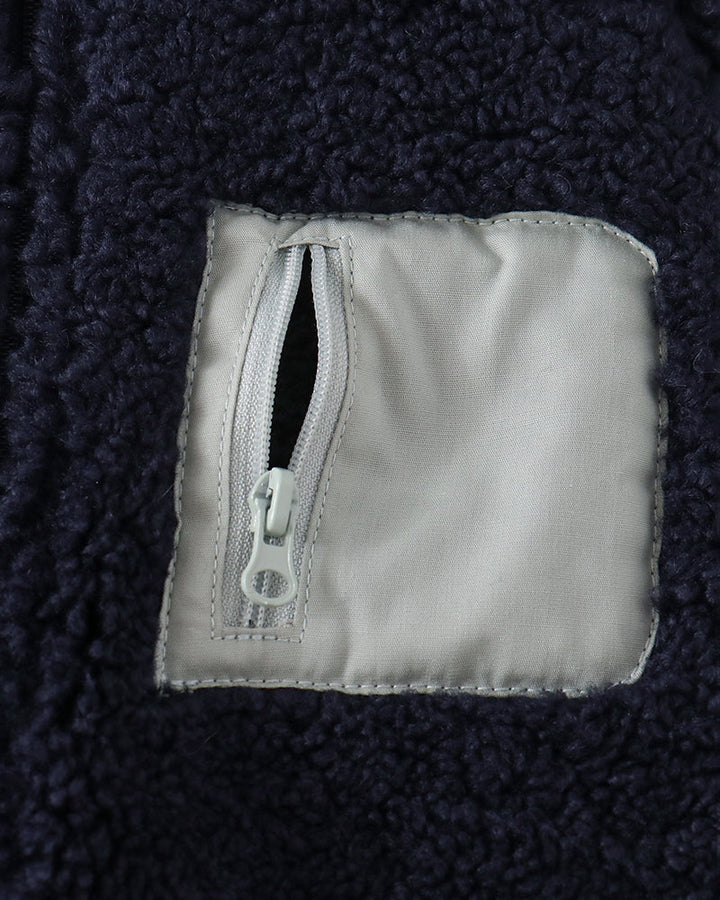 Navy fleece jacket close-up of chest pocket with zipper tab and label patch
